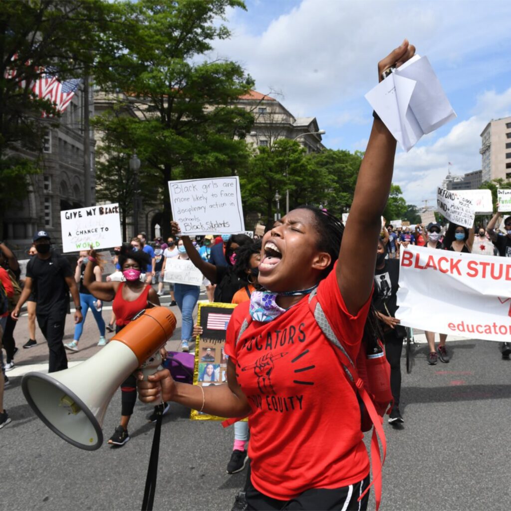Following the footsteps of her great-grandmother, Ida B. Wells, Michelle Duster fights for equity with hand raised fist, megaphone in other and cries for justice in the streets